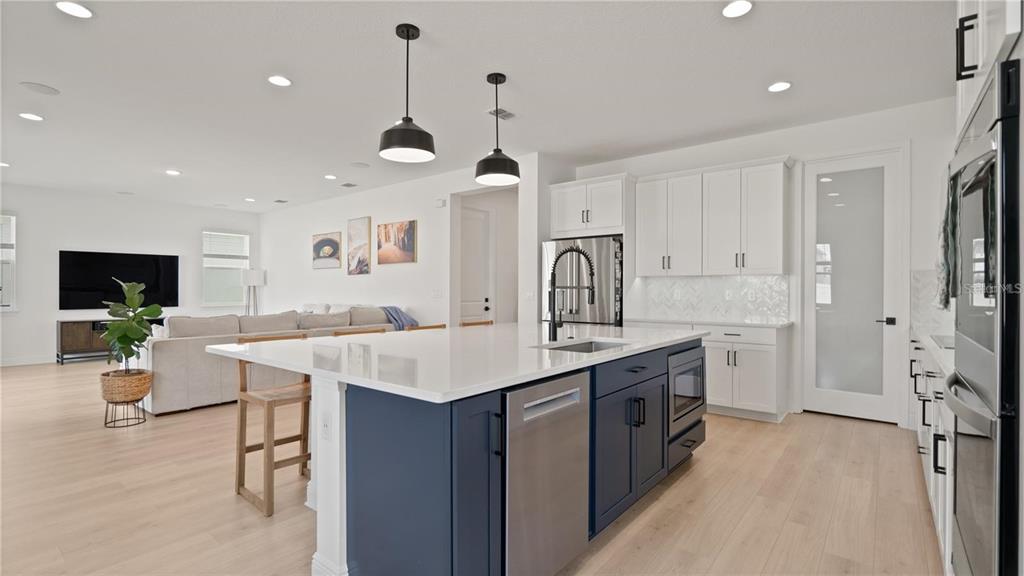 A modern kitchen features a blue island with a white countertop and white cabinetry — 15239 LAKE LAMONIA ST, WINTER GARDEN, FL