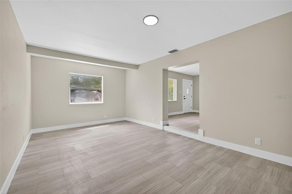 An empty room with light wood-look flooring, beige walls, and a recessed entryway — 413 COUNTRY CLUB DRIVE, OLDSMAR, FL