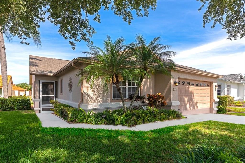 A single-story house with a tan exterior, a two-car garage, and palm trees in front — 4734 RAINTREE STREET CIRCLE E, BRADENTON, FL