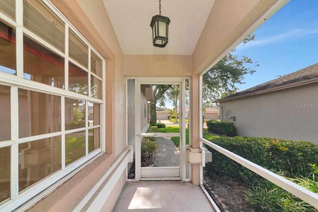 A screened-in porch features a concrete floor, a hanging light fixture, and a screen door — 4734 RAINTREE STREET CIRCLE E, BRADENTON, FL