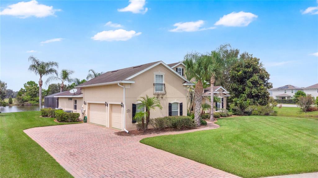 A two-story house with a brick paver driveway, a two-car garage, and palm trees — 1605 MARINA LAKE DRIVE, KISSIMMEE, FL