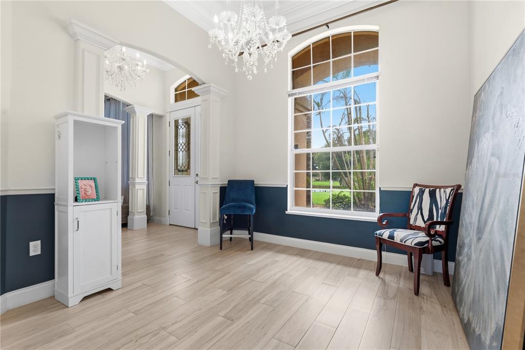 A bright entryway features light wood floors, a crystal chandelier, and blue wainscoting — 1605 MARINA LAKE DRIVE, KISSIMMEE, FL