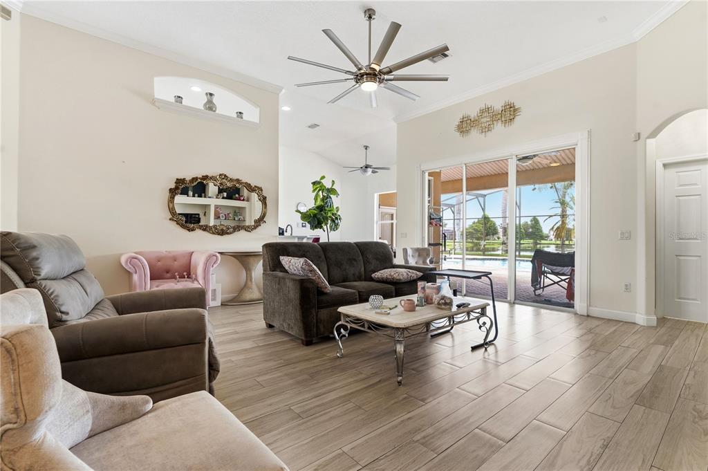 A living room features tile flooring, a large ceiling fan, and sliding glass doors to a pool — 1605 MARINA LAKE DRIVE, KISSIMMEE, FL