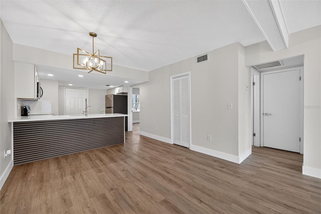 A kitchen with a breakfast bar and wood-look flooring opens into a living area — 9824 POCONO STREET, PORT RICHEY, FL