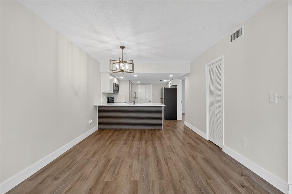 A dining area with wood-look flooring leads to a kitchen featuring a dark slatted breakfast bar — 9824 POCONO STREET, PORT RICHEY, FL