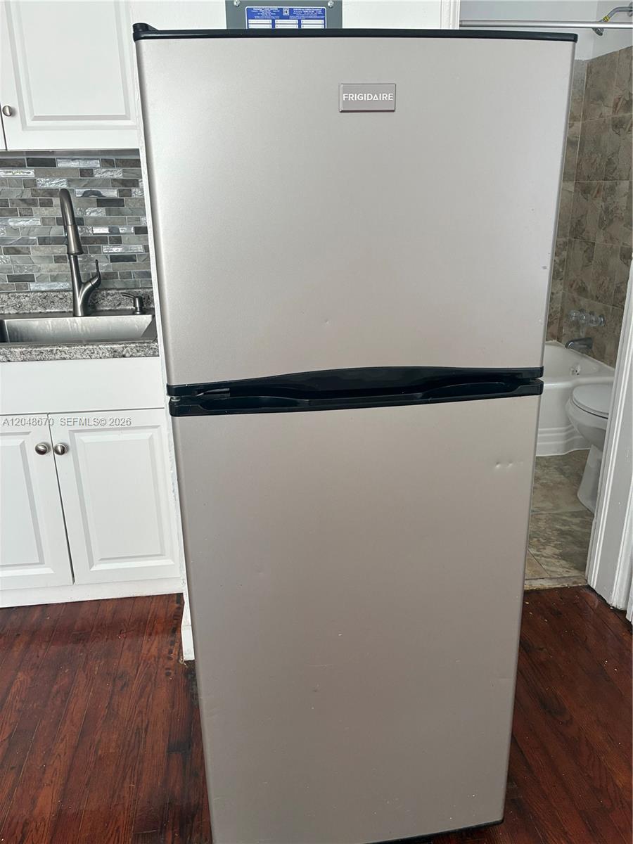 A stainless steel Frigidaire refrigerator stands in a room with white cabinets and wood flooring — 8020 Abbott Ave # 6, Miami Beach FL 33141, MIAMI BEACH, FL