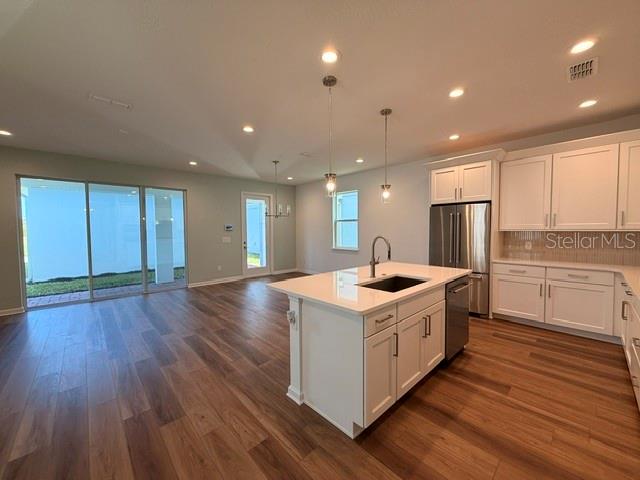 A modern kitchen with white cabinets, a center island, and wood-look flooring — 2592 LONG PINE AVENUE, APOPKA, FL