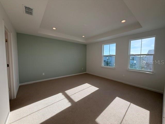 An empty bedroom features a tray ceiling, light green accent wall, and beige carpeting — 2592 LONG PINE AVENUE, APOPKA, FL