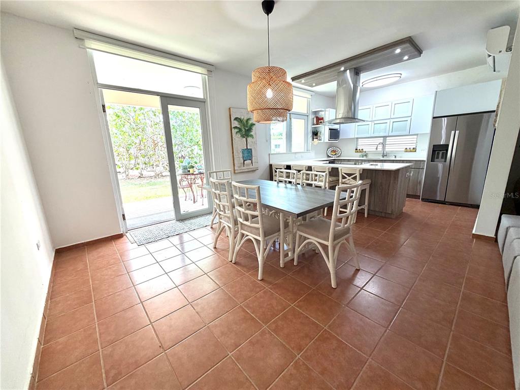 A dining area with a wooden table and chairs sits adjacent to a modern kitchen — 693 NORTH COAST VILLAGE UNIT 236, VEGA ALTA, PR