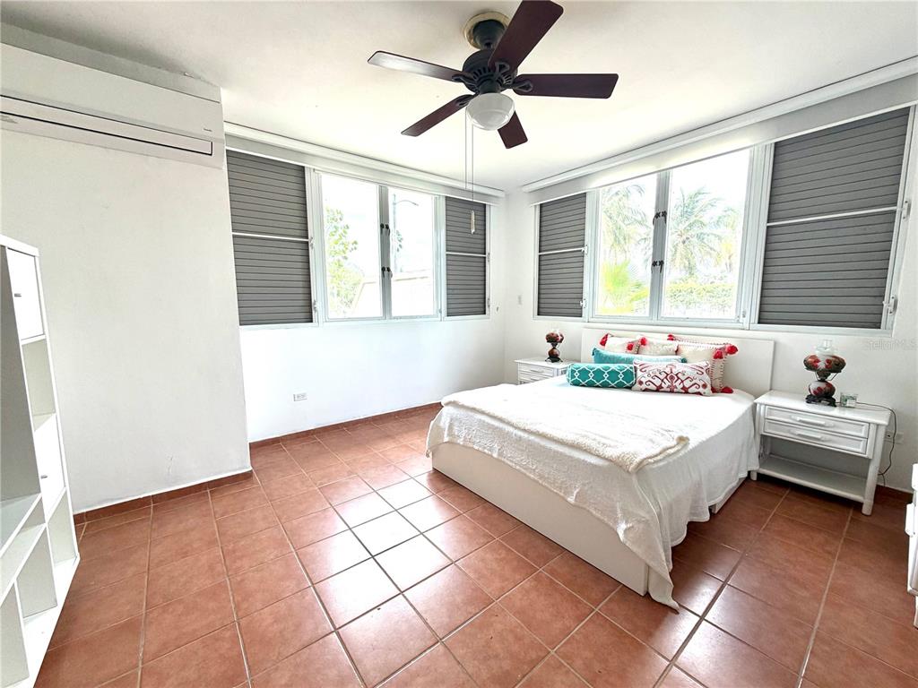 A bedroom features terracotta tile floors, a ceiling fan, and large windows with blinds — 693 NORTH COAST VILLAGE UNIT 236, VEGA ALTA, PR
