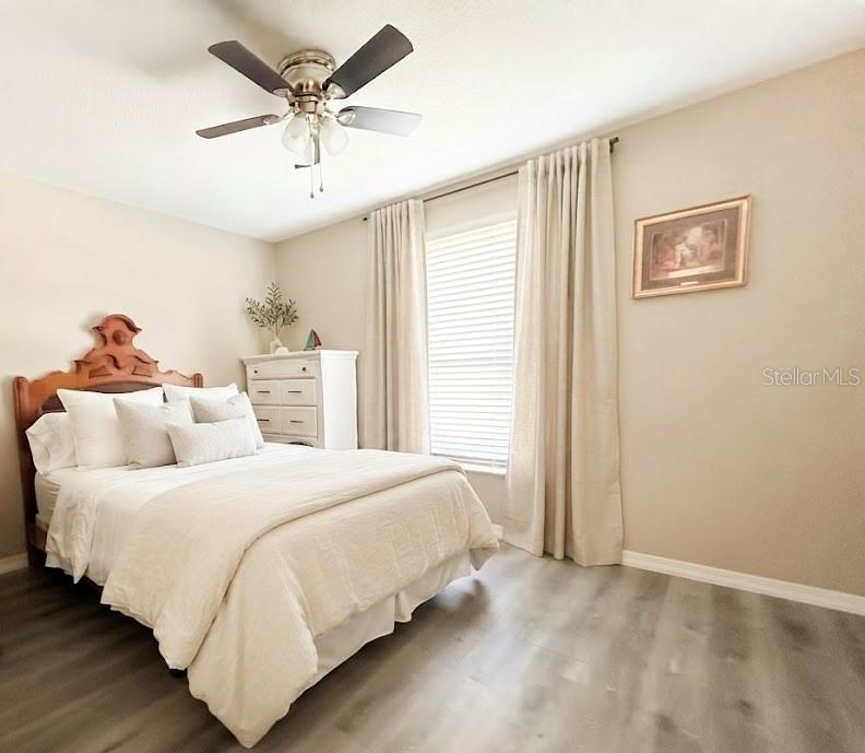 A bedroom features a tray ceiling, light wood-look flooring, a bed with white bedding, and glass doors — 2632 SW 175TH LOOP, OCALA, FL