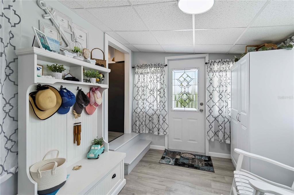 An entryway features a white hall tree, a front door with decorative glass, and light flooring — 1100 UNIVERSITY PARKWAY UNIT 54, SARASOTA, FL