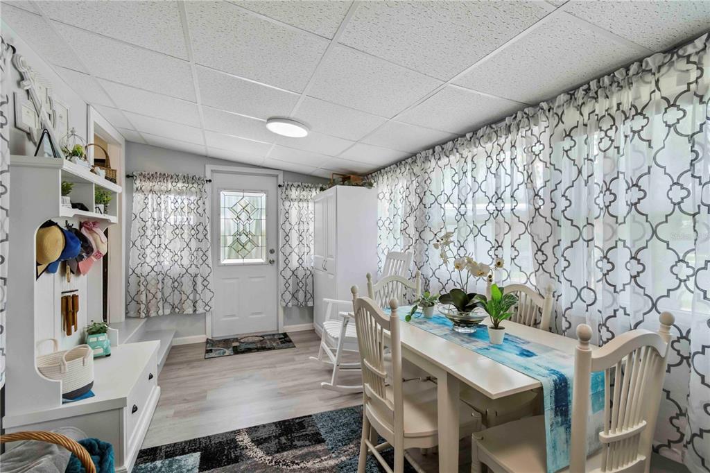A dining room features a white table, chairs, a patterned curtain wall, and light flooring — 1100 UNIVERSITY PARKWAY UNIT 54, SARASOTA, FL