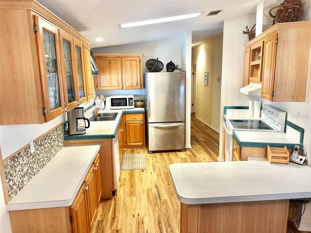 A kitchen features wood cabinets, stainless steel appliances, and a tiled backsplash — 11208 101ST STREET UNIT 115, LARGO, FL