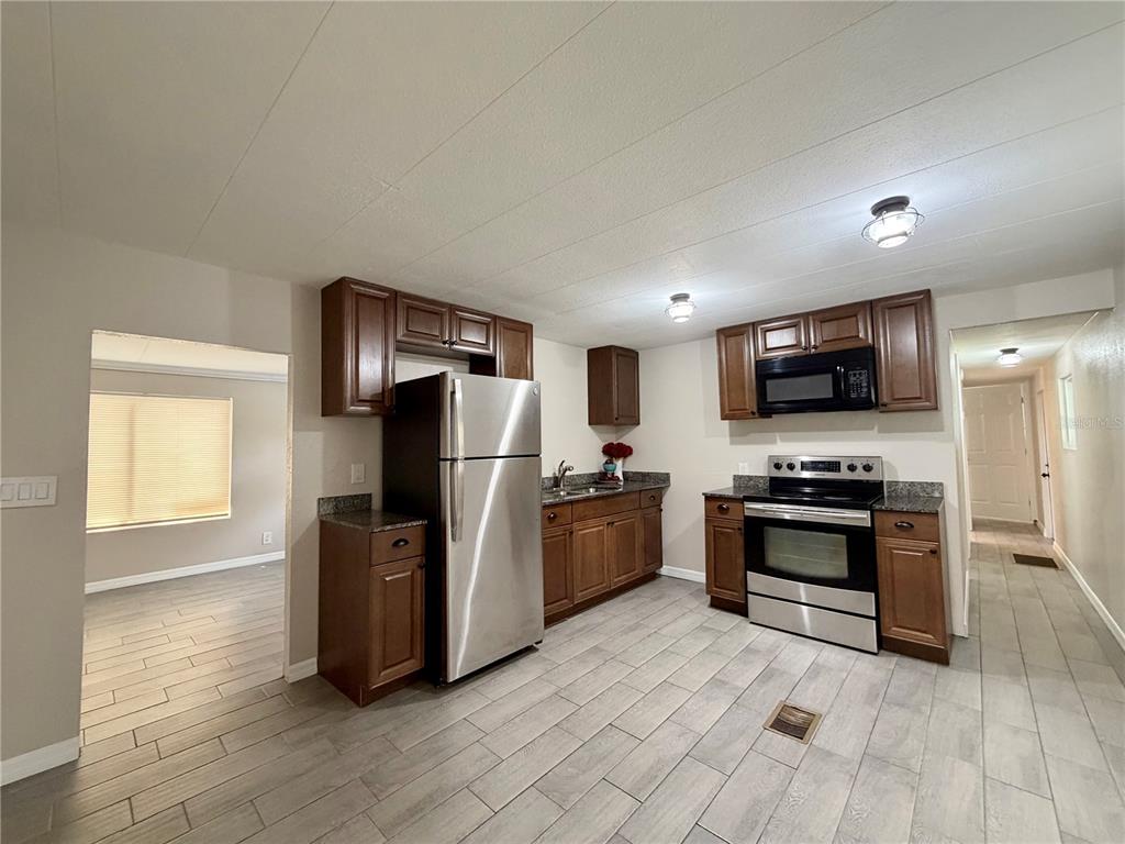 A kitchen with wood cabinets, stainless steel appliances, and light-colored tile flooring — 7037 LOFTY DRIVE, PORT RICHEY, FL