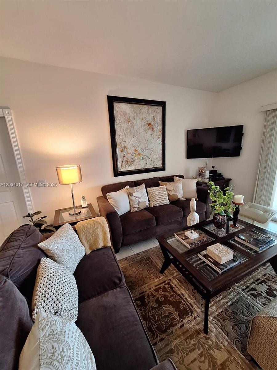 A living room features two brown sofas, a glass-topped coffee table, and wall-mounted television — 2104 Tigris Dr, West Palm Beach FL 33411, WEST PALM BEACH, FL