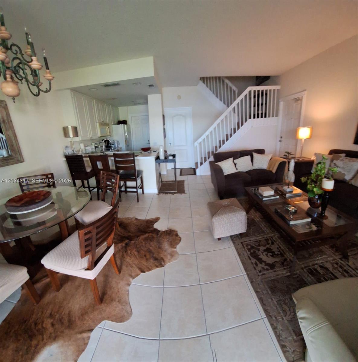 An open-concept living and dining area features tile flooring, a staircase, and a kitchen — 2104 Tigris Dr, West Palm Beach FL 33411, WEST PALM BEACH, FL
