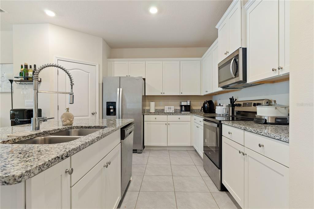 A kitchen features white cabinets, granite countertops, stainless steel appliances, and a central island — 117 REDBUD ROAD, PALM COAST, FL