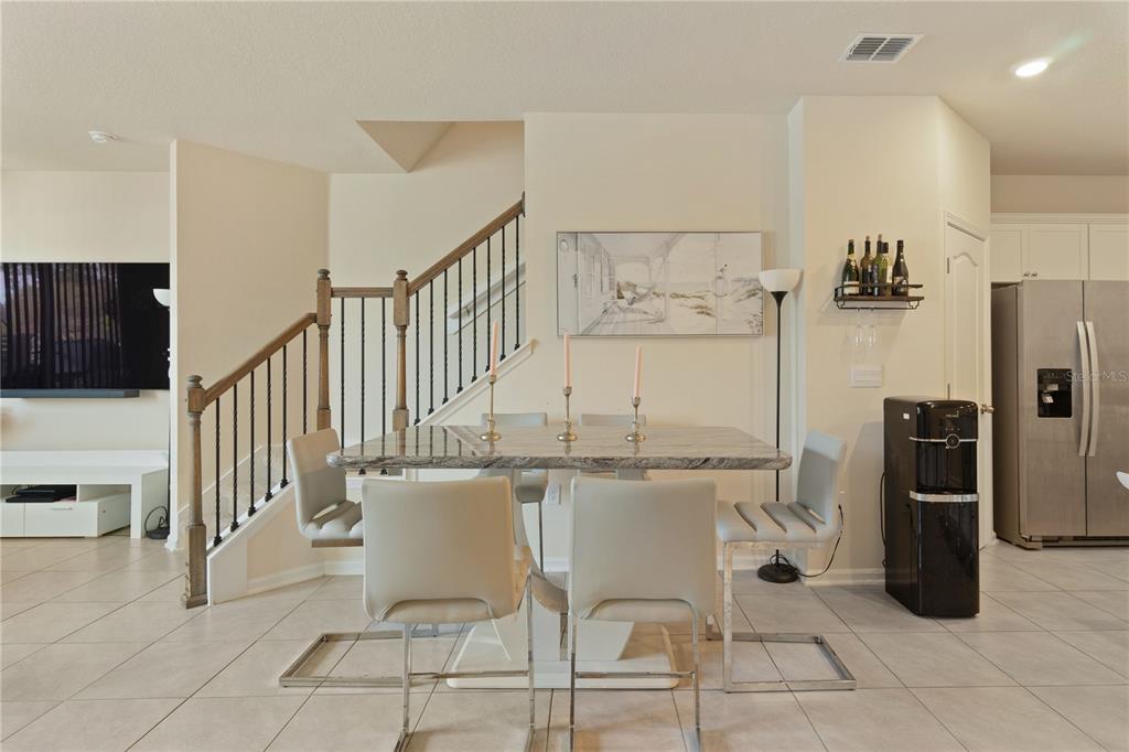 A dining area features a granite-topped table, four modern chairs, and a staircase with railings — 117 REDBUD ROAD, PALM COAST, FL