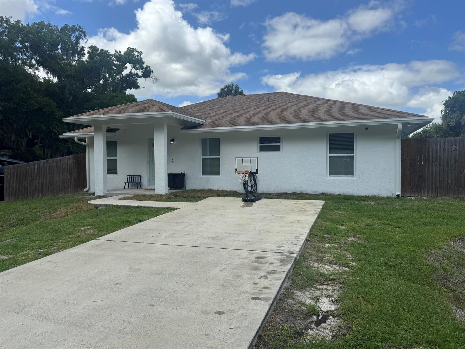 A white single-story house with a brown roof, concrete driveway, and a basketball hoop — 1691 SW 11th Street, Okeechobee FL 34974, OKEECHOBEE, FL