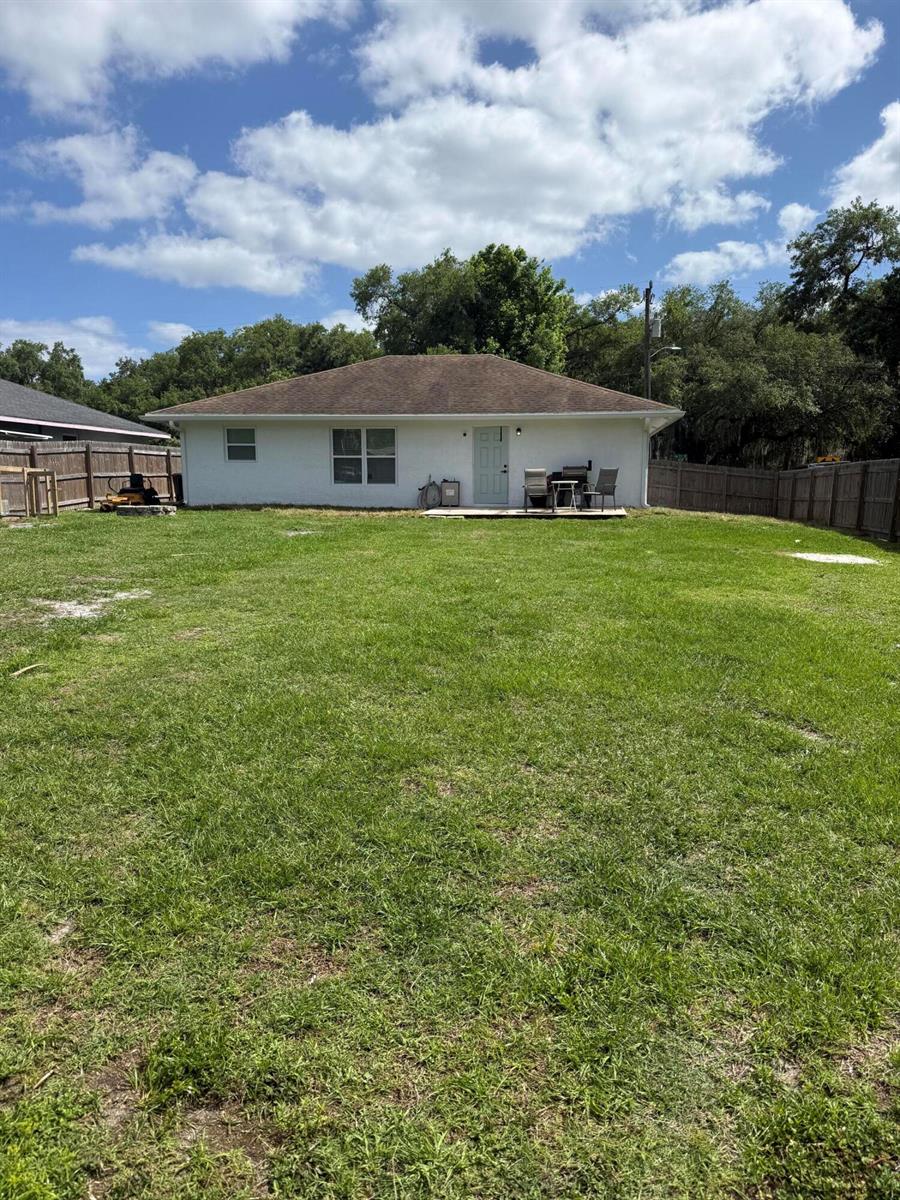 The exterior view shows the back of a white house with a large grassy yard — 1691 SW 11th Street, Okeechobee FL 34974, OKEECHOBEE, FL