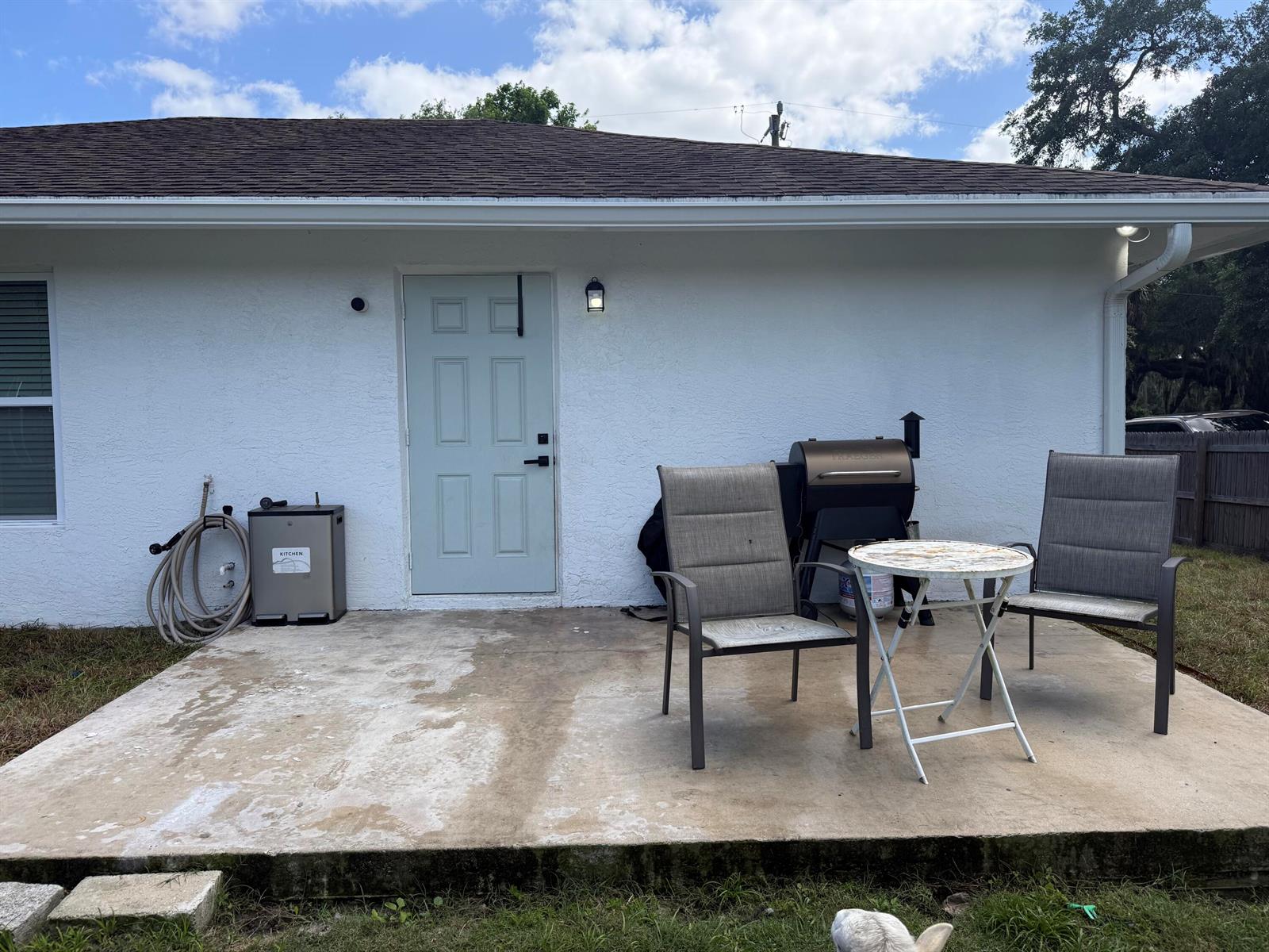 A concrete patio features two chairs, a small table, a grill, and a light-colored door — 1691 SW 11th Street, Okeechobee FL 34974, OKEECHOBEE, FL