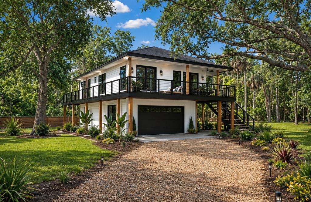 A two-story house with white siding, a black garage door, and a wraparound balcony — 707 GEORGE STREET S, TARPON SPRINGS, FL