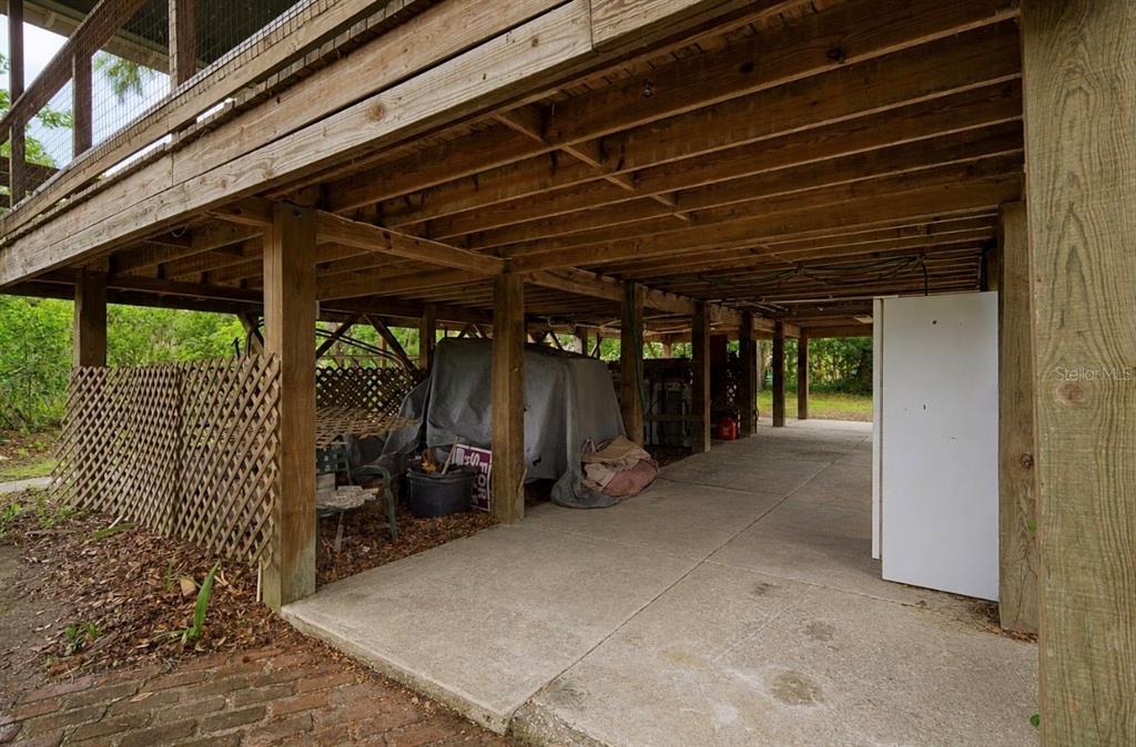 A concrete patio sits beneath an elevated wooden deck supported by vertical posts — 707 GEORGE STREET S, TARPON SPRINGS, FL