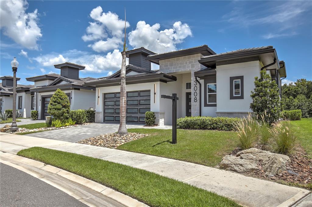 A modern single-story house with a stone facade, dark trim, and a paved driveway — 3008 KENSINGTON AVENUE, DAVENPORT, FL