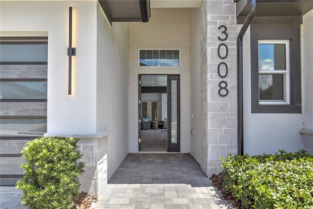 The front entrance features a paved walkway, a modern glass door, and stone siding — 3008 KENSINGTON AVENUE, DAVENPORT, FL