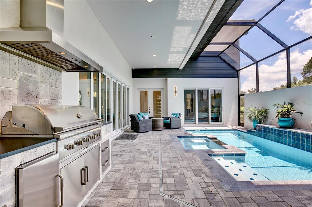 A covered outdoor kitchen and patio area features a grill, pool, and spa enclosure — 3008 KENSINGTON AVENUE, DAVENPORT, FL
