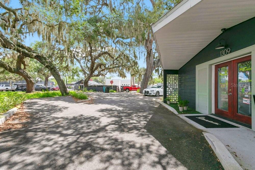 An exterior view of a building entrance with a paved parking area and large trees — 1309 WILFRED DRIVE, ORLANDO, FL