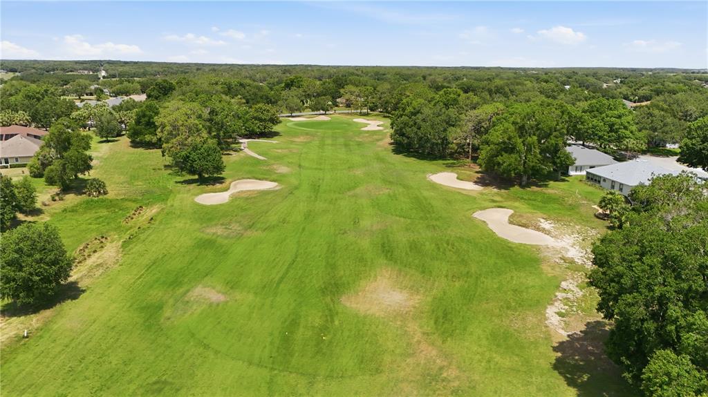An aerial view of a golf course fairway lined with trees and residential homes — 5453 GROVE MANOR, LADY LAKE, FL
