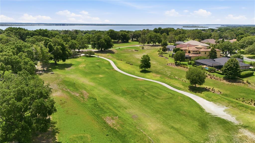 An aerial view of a golf course fairway with a cart path and nearby houses — 5453 GROVE MANOR, LADY LAKE, FL