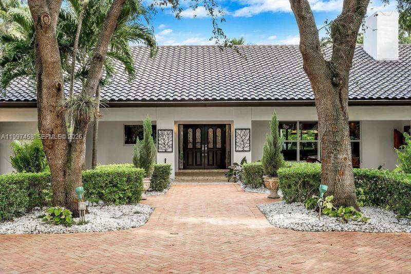 A brick walkway leads to the front entrance of a house with a tiled roof — 7405 SW 79th Ct, Miami FL 33143, MIAMI, FL