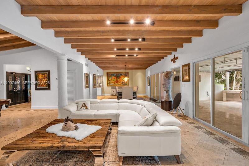 A spacious living room features a white sectional sofa, wood-beamed ceiling, and tile flooring — 7405 SW 79th Ct, Miami FL 33143, MIAMI, FL