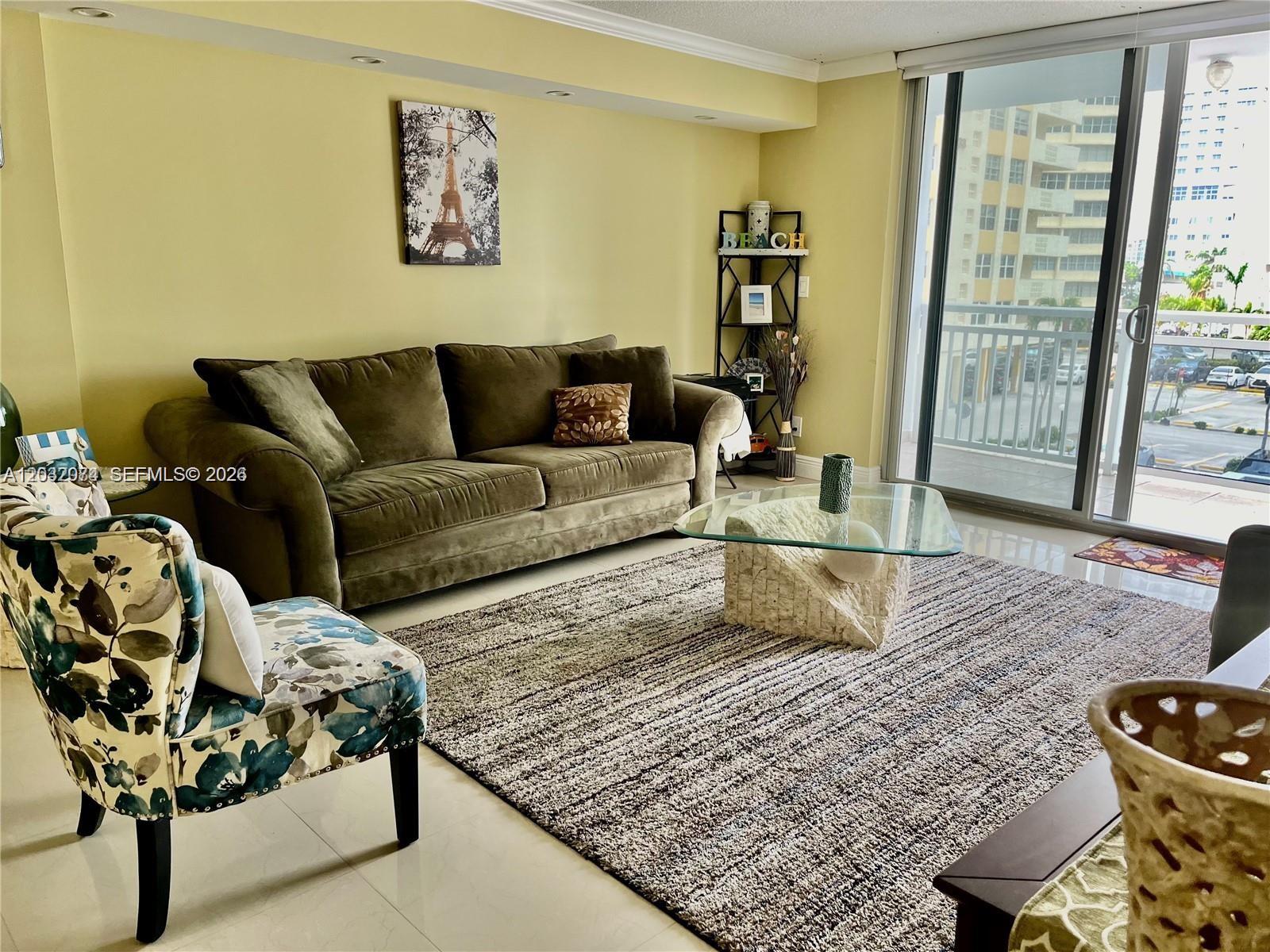 A living room features a green sofa, a floral armchair, and a glass-topped coffee table — 1849 S Ocean Dr # 0, Hallandale Beach FL 33009, HALLANDALE BEACH, FL