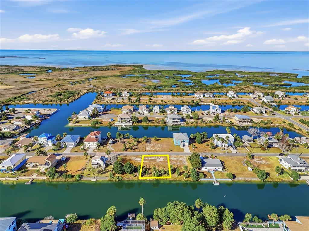 An aerial view shows a vacant waterfront lot highlighted in yellow within a residential neighborhood — 3310 GARDENIA DRIVE, HERNANDO BEACH, FL