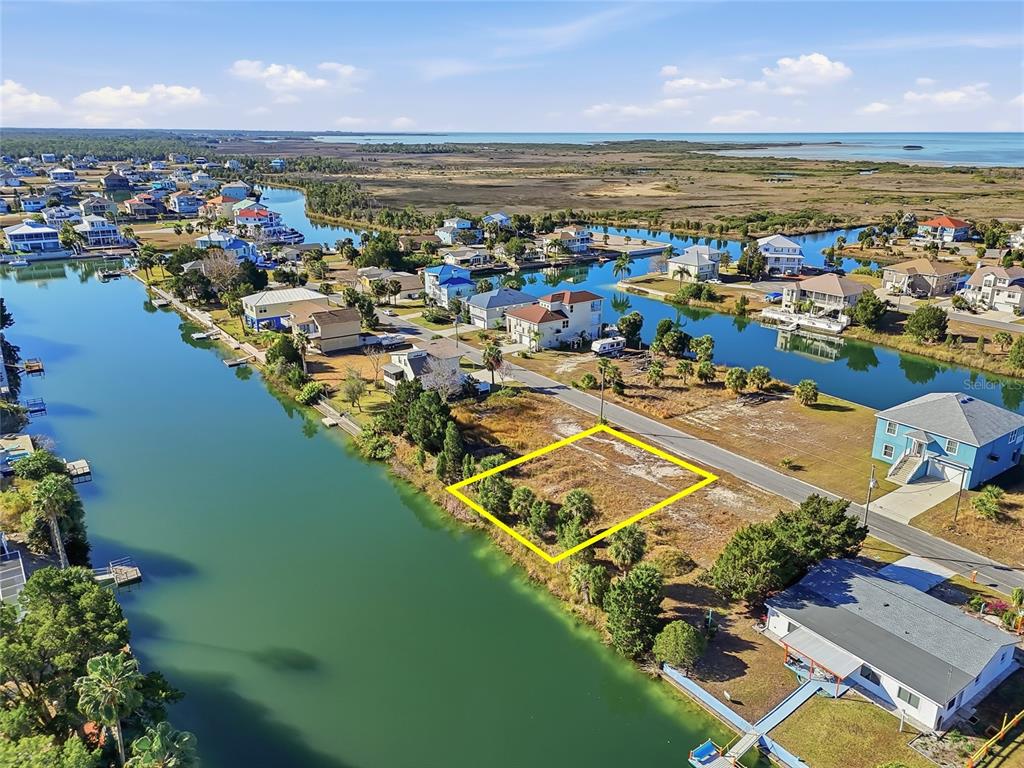 An aerial view shows a vacant waterfront lot outlined in yellow along a canal — 3310 GARDENIA DRIVE, HERNANDO BEACH, FL