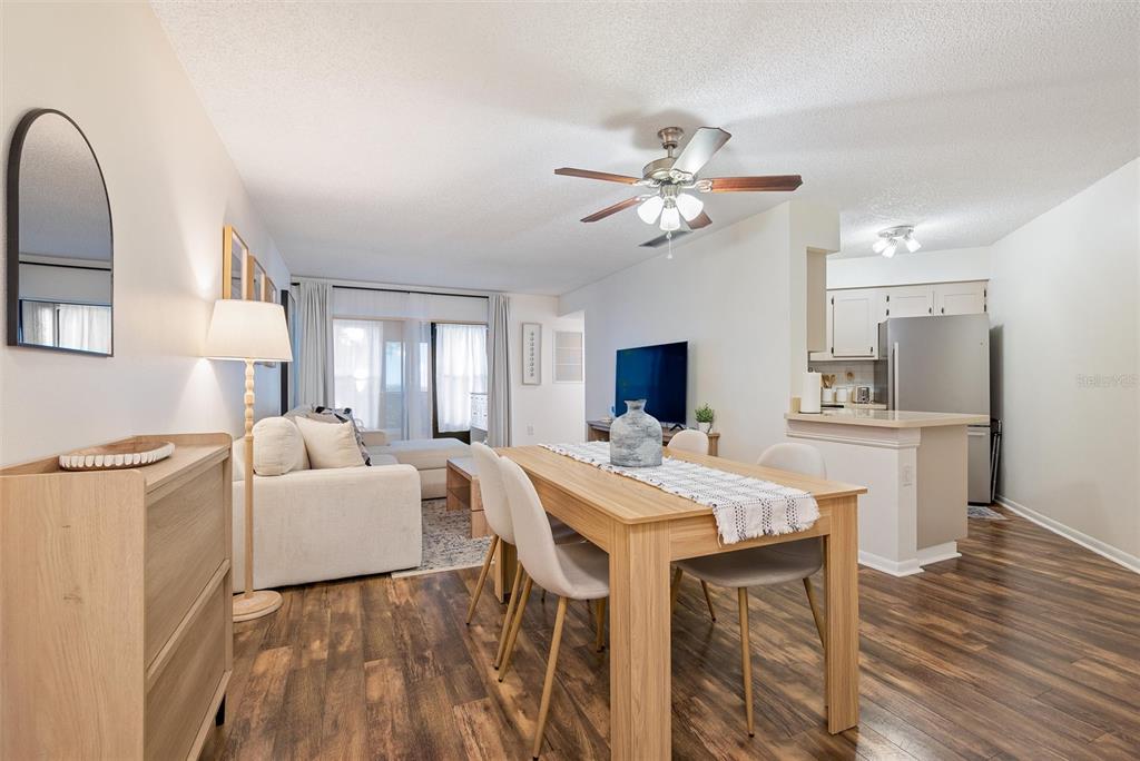 An open-concept living and dining area features wood-look flooring, a ceiling fan, and kitchen access — 3806 SOUTHPOINTE DRIVE UNIT L4, ORLANDO, FL