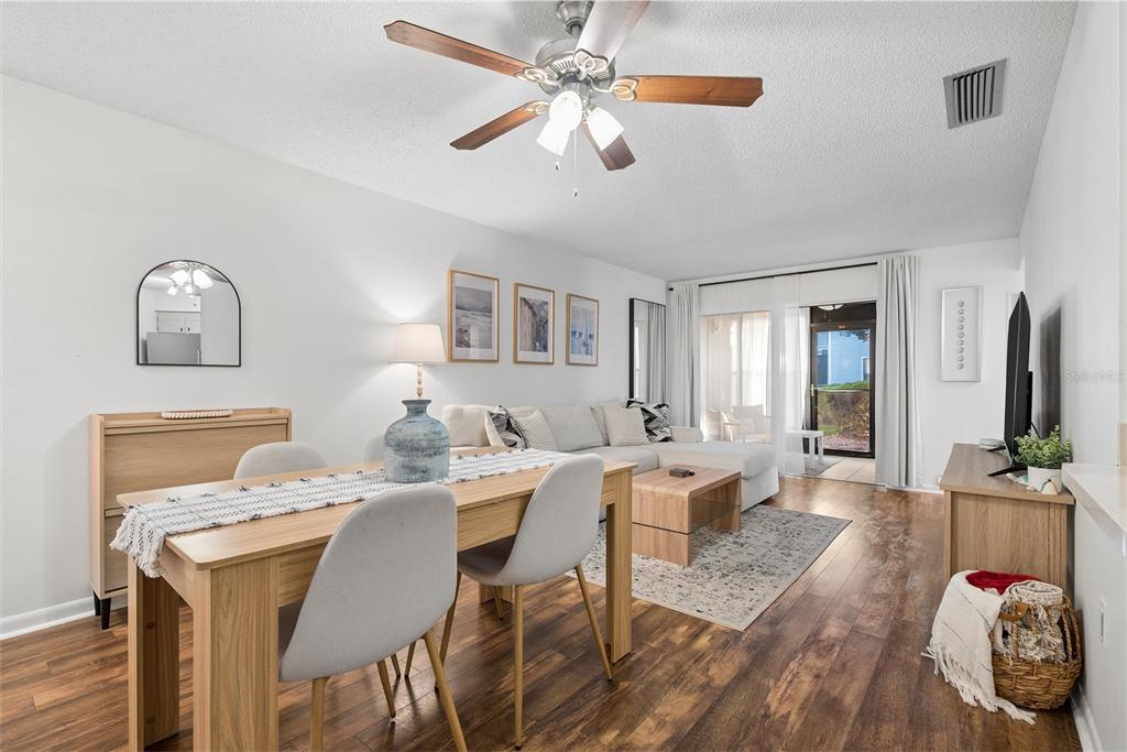 A dining area and living room feature wood-look flooring, a ceiling fan, and sliding glass doors — 3806 SOUTHPOINTE DRIVE UNIT L4, ORLANDO, FL