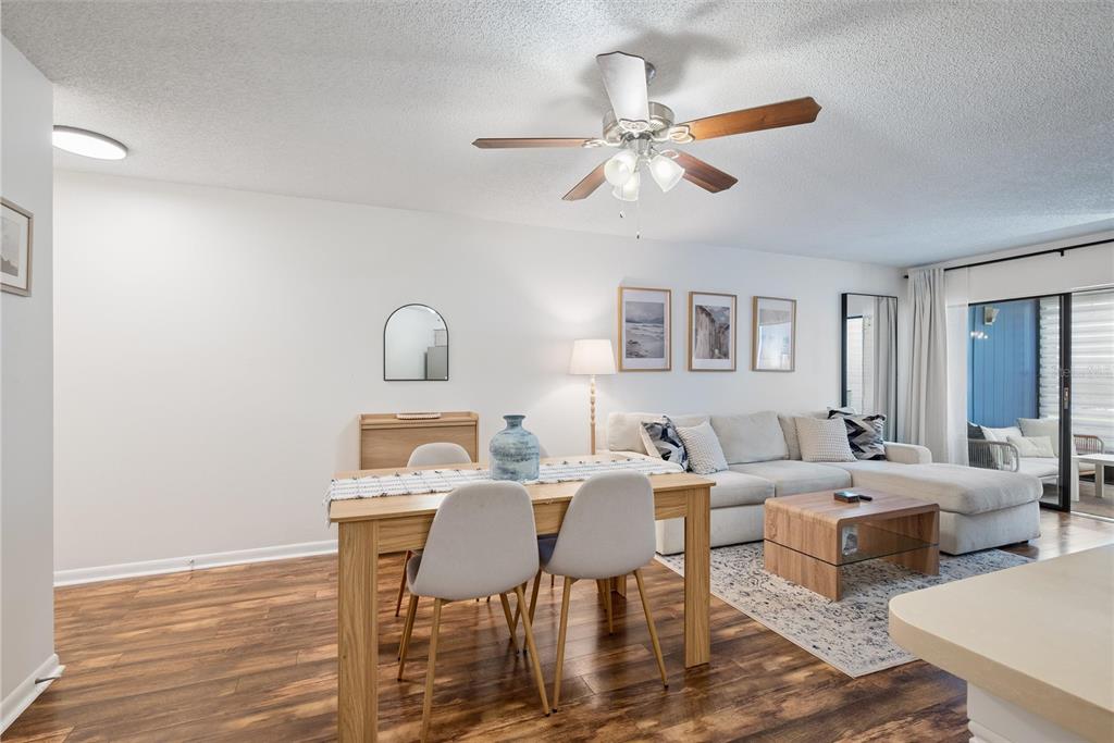 An open-concept living and dining area features wood-look flooring, a ceiling fan, and neutral furniture — 3806 SOUTHPOINTE DRIVE UNIT L4, ORLANDO, FL