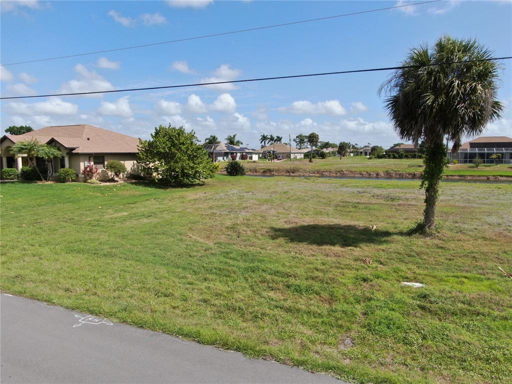 A vacant grassy lot sits next to a house with a palm tree nearby — 35 & 37 TOURNAMENT ROAD, ROTONDA WEST, FL