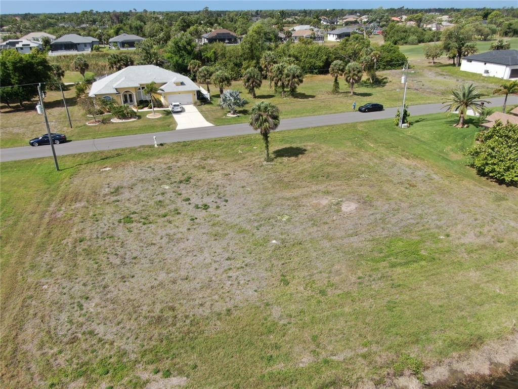 An aerial view shows a vacant grassy lot bordered by a road and a house — 35 & 37 TOURNAMENT ROAD, ROTONDA WEST, FL
