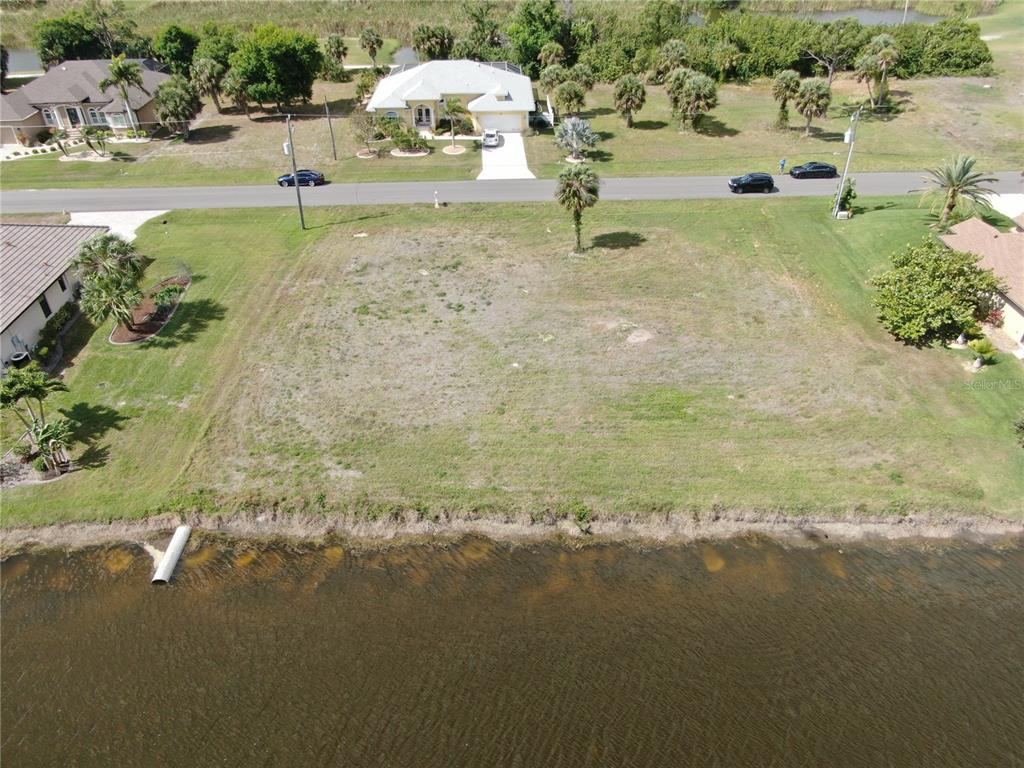 An aerial view of a vacant waterfront lot located across the street from residential houses — 35 & 37 TOURNAMENT ROAD, ROTONDA WEST, FL