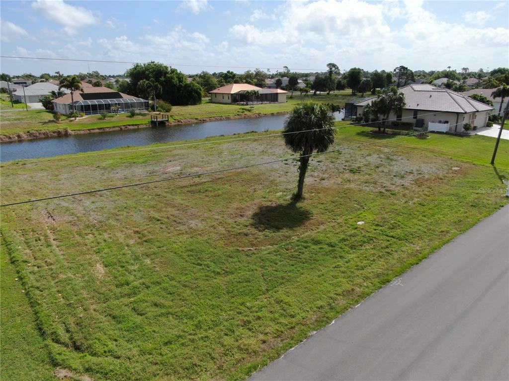 An aerial view shows a vacant grassy lot next to a canal and residential houses — 35 & 37 TOURNAMENT ROAD, ROTONDA WEST, FL