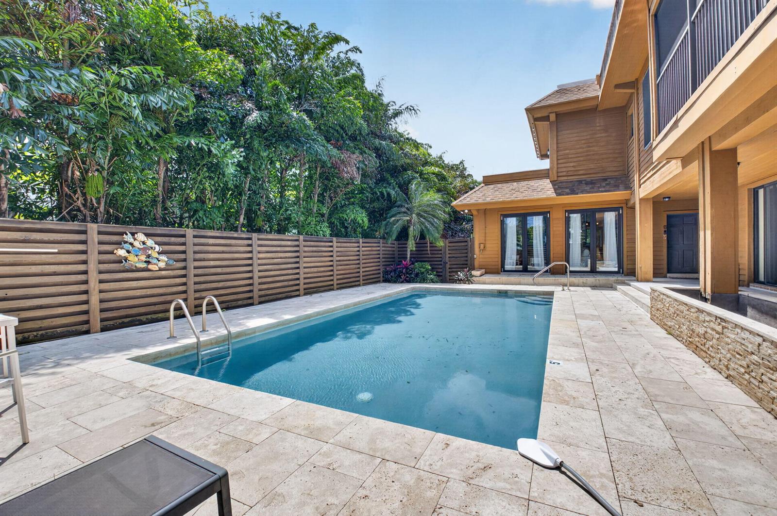 A rectangular swimming pool sits on a stone patio beside a two-story wooden house — 122 Andrews Avenue # B, Delray Beach FL 33483, DELRAY BEACH, FL