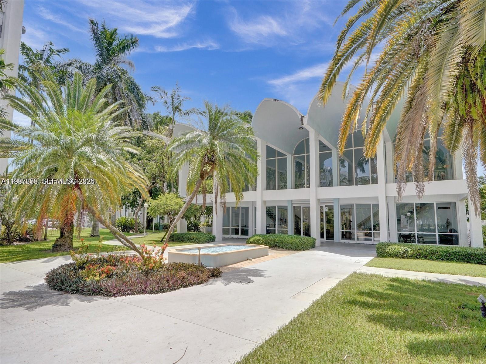 The exterior of a white building features a vaulted roofline, large windows, and palm trees — 488 NW 165th St Rd # 408, Miami FL 33169, MIAMI, FL