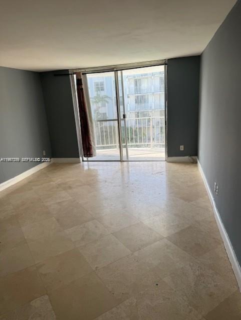 An empty room with light-colored tile flooring and a sliding glass door leading to a balcony — 488 NW 165th St Rd # 408, Miami FL 33169, MIAMI, FL