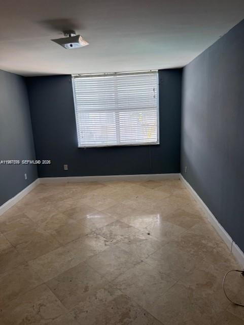 An empty room features dark gray walls, light-colored tile flooring, and a window with blinds — 488 NW 165th St Rd # 408, Miami FL 33169, MIAMI, FL